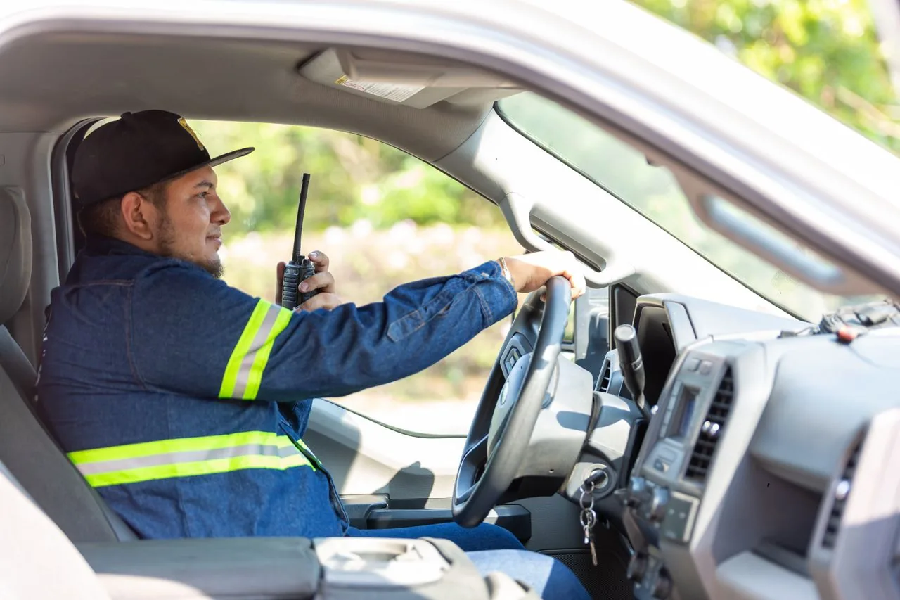 A crew member in a truck cab talking on a handheld radio