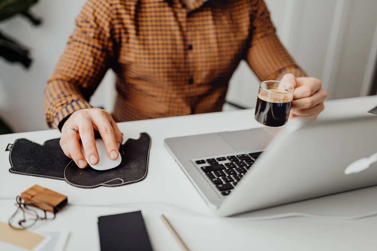 An owner working through paperwork on a laptop with a coffee