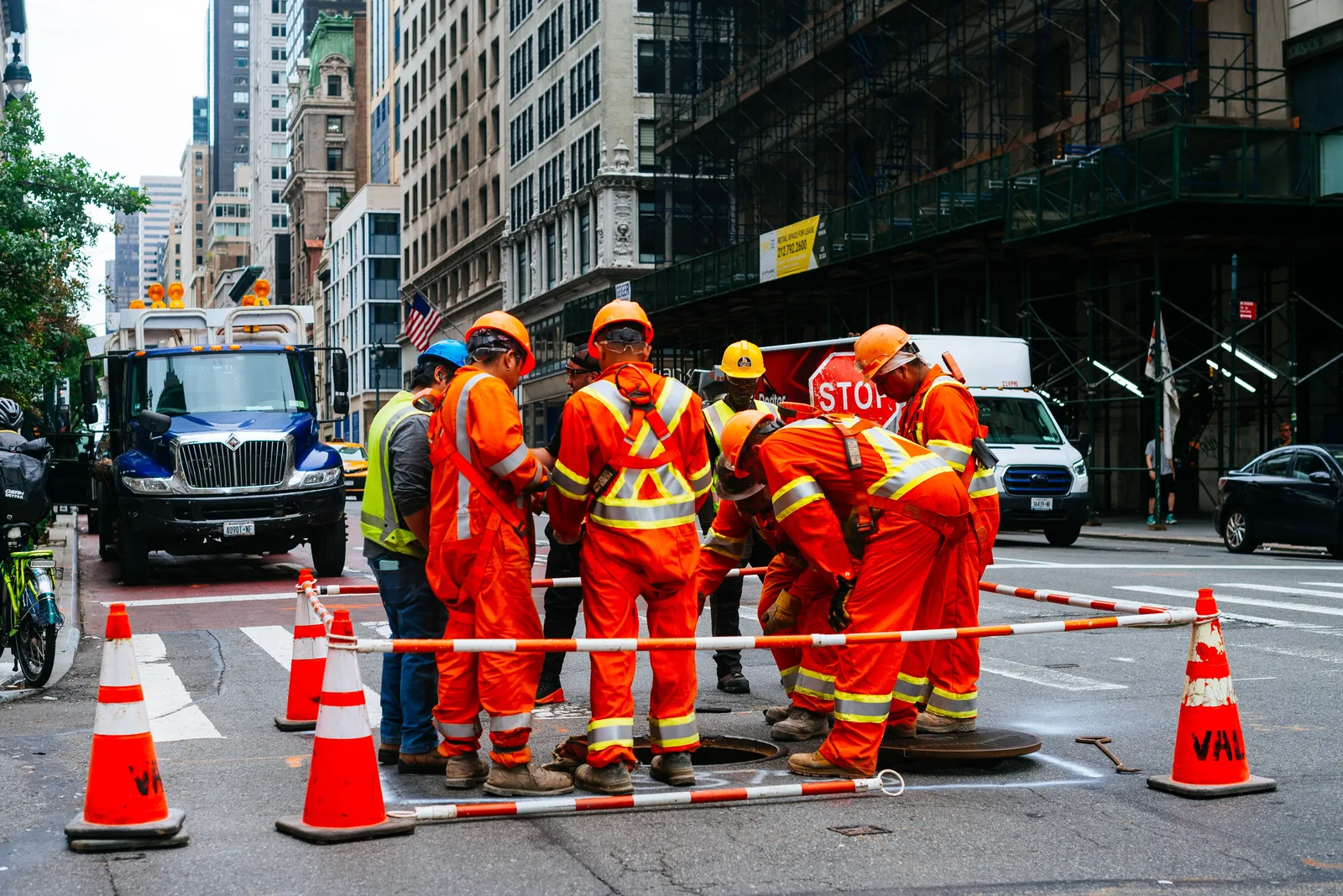 A road crew in high-visibility gear gathered around a job in the street