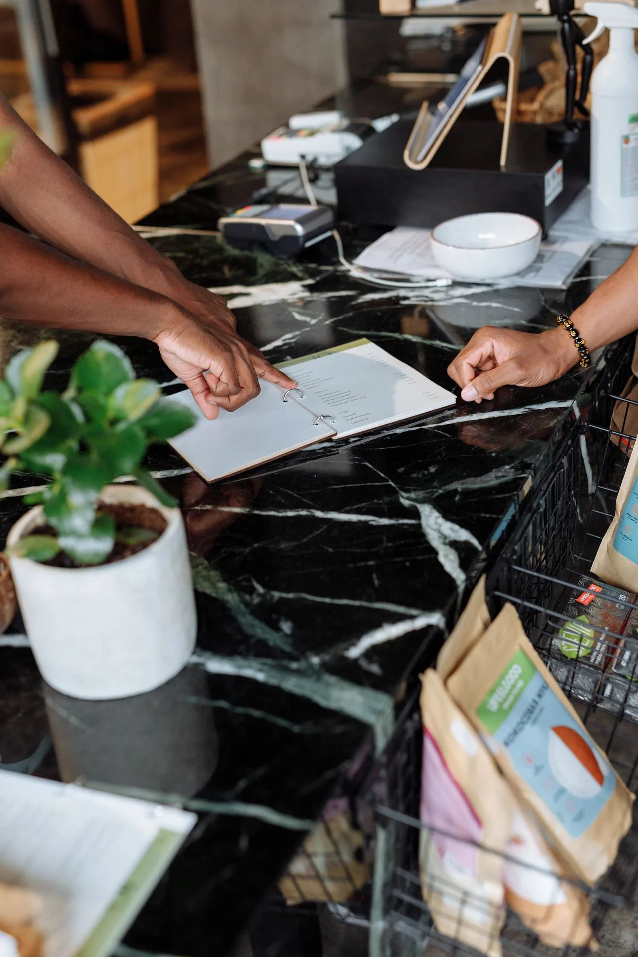 Staff at a host station taking a booking on a tablet beside paperwork
